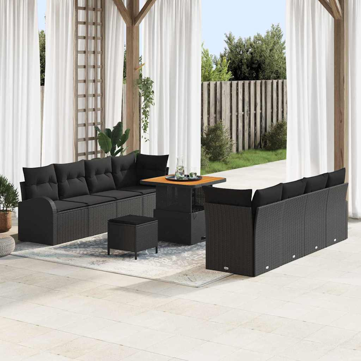 Garten-Terrassenset mit schwarzer Korbmöbel. Enthält Sofas, einen Tisch und eine Fußstütze. Weiße Vorhänge und eine Holzpergola rahmen die Szene ein.