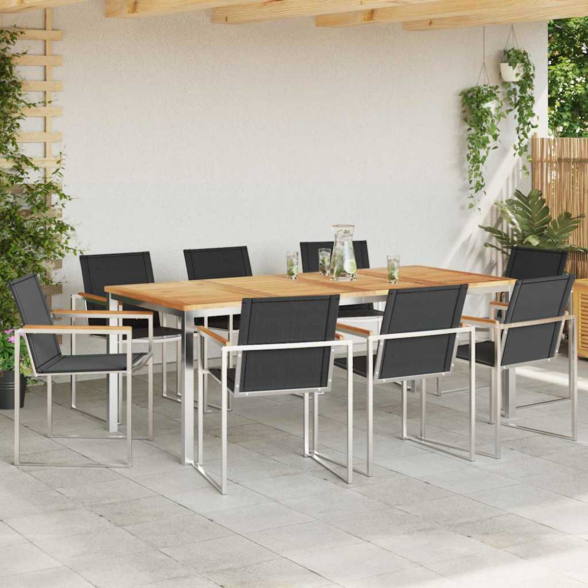 Juego de comedor al aire libre. Mesa de madera con sillas negras. Fondo blanco con plantas colgantes y valla de bambú.
