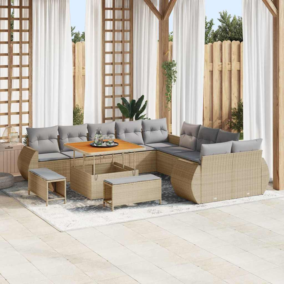 Outdoor-Sitzbereich mit Korbmöbeln, grauen Kissen, Holztisch, weißen Vorhängen und Holzzaun im Hintergrund.