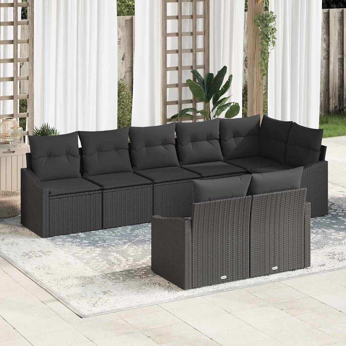 Outdoor-Ecksofa mit schwarzen Kissen. Weiße Vorhänge und Pflanzen im Hintergrund. Ein Teppich liegt auf der Terrasse.