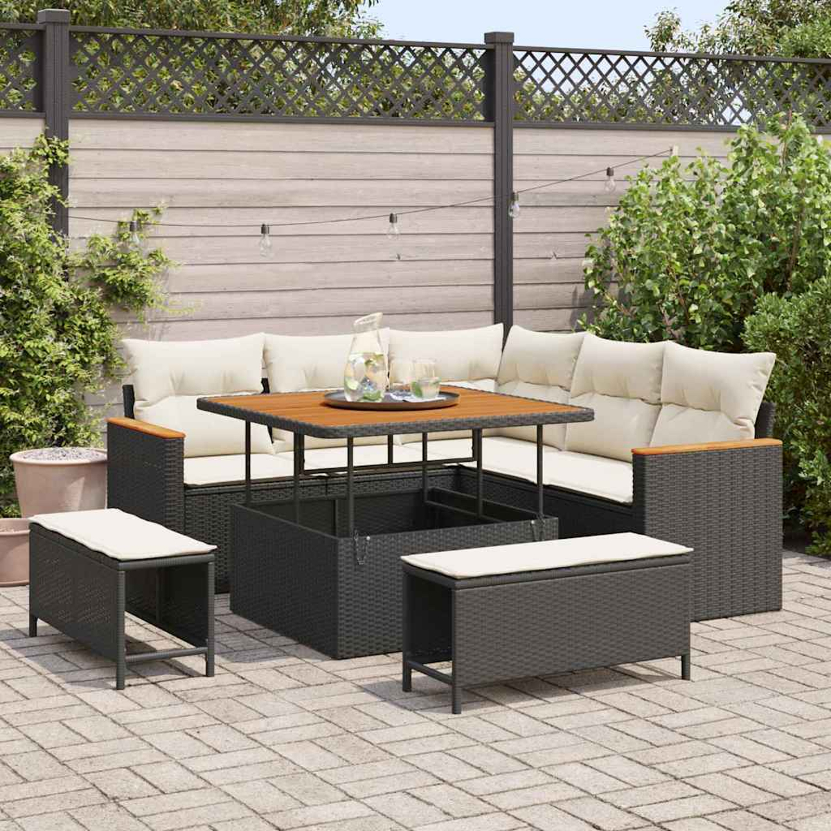 Juego de patio exterior con muebles de mimbre negro, cojines beige y una mesa de madera. Incluye sofá, dos bancos y patio de ladrillo.