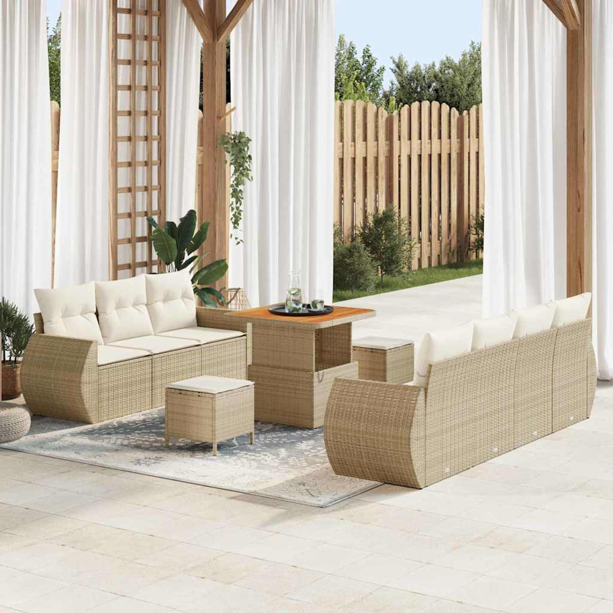 Außenbereich mit Rattanmöbeln, cremefarbenen Kissen und einem Holztisch. Weiße Vorhänge und ein Holzzaun sind im Hintergrund.