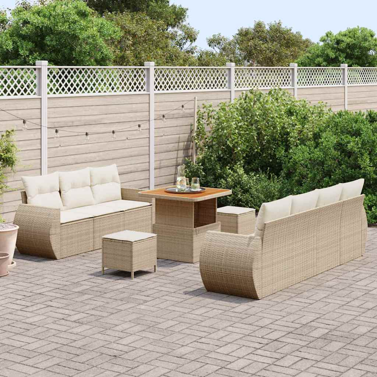 Garten-Set mit beigen Korbmöbeln. Enthält zwei Sofas, zwei Hocker und einen Tisch auf einer Ziegelterrasse. Im Hintergrund ein Zaun.
