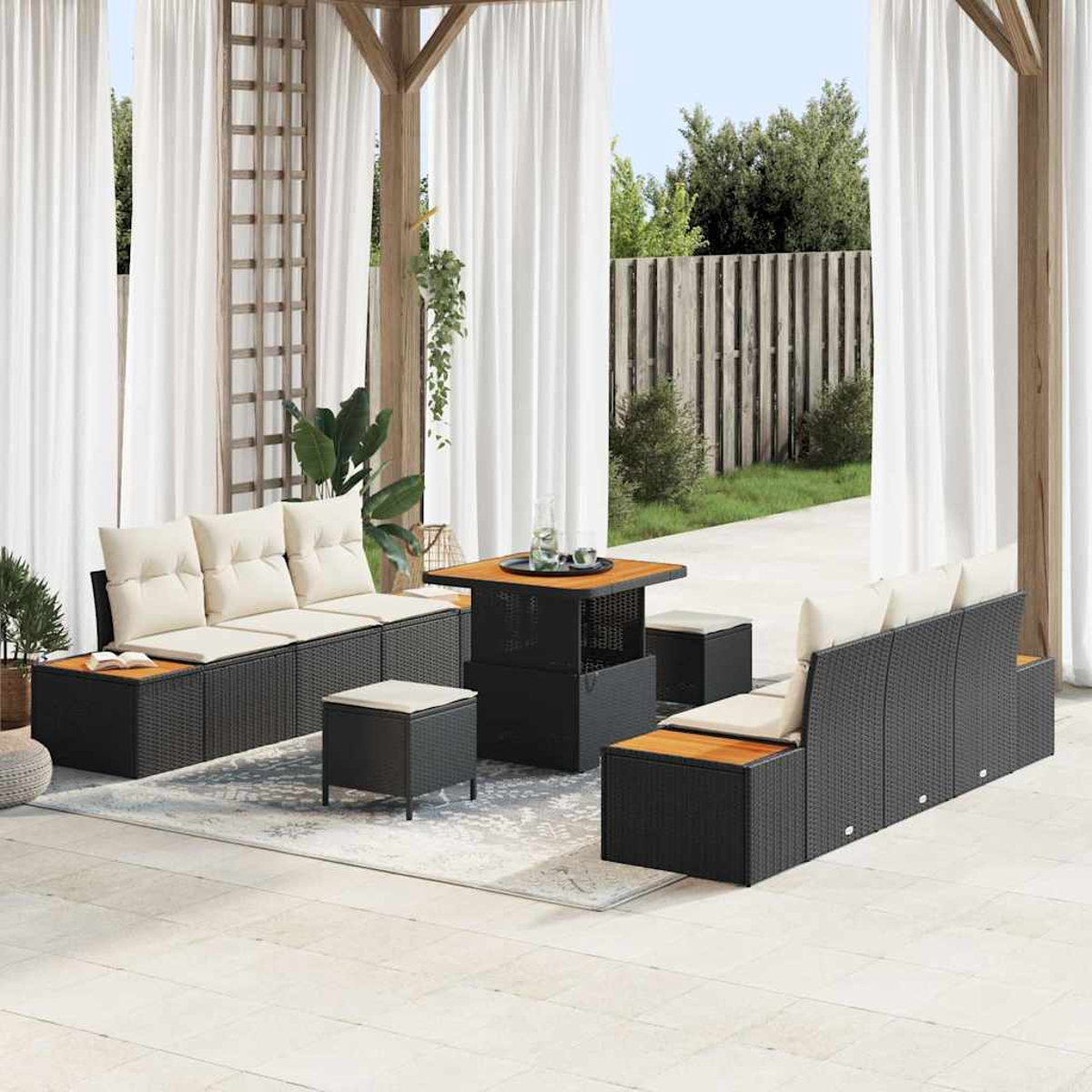 Garten-Terrassenset mit schwarzen Korbmöbeln und beigen Kissen, einem quadratischen Tisch und weißen Vorhängen. Grün und ein Zaun sind sichtbar.