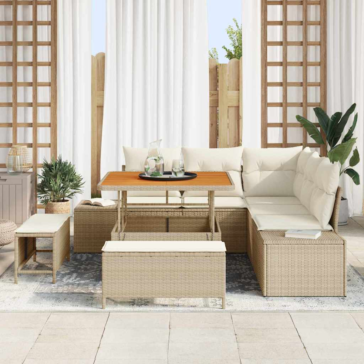 Outdoor-Sitzbereich mit Rattanmöbeln. Ein Tisch mit Tablett, Gläsern und einem Krug. Weiße Vorhänge und Pflanzen im Hintergrund.
