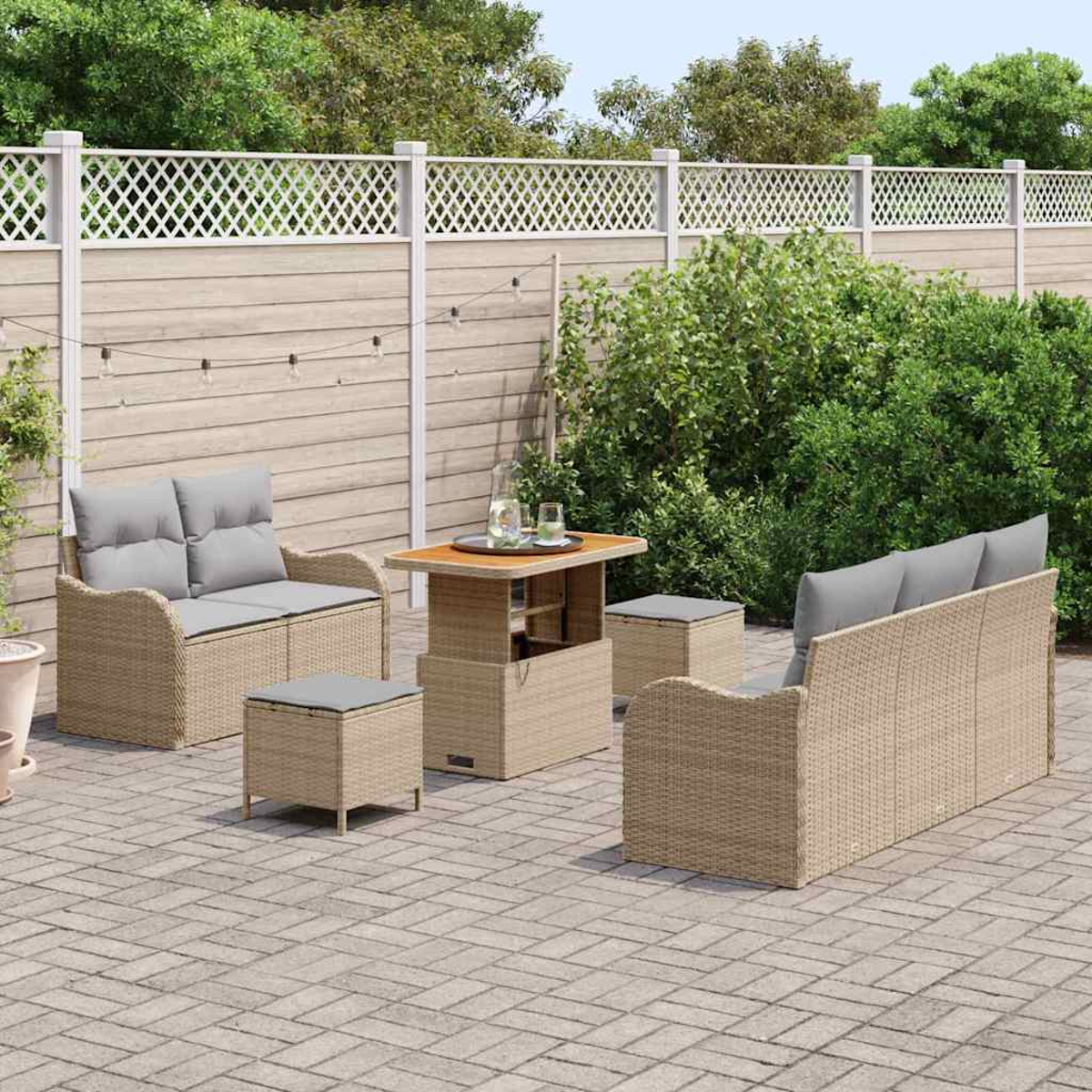 Terrassenmöbel-Set auf einer Steinterrasse. Enthält Sofa, Loveseat, Tisch und Ottomane. Ein Zaun und Grünzeug sind im Hintergrund.