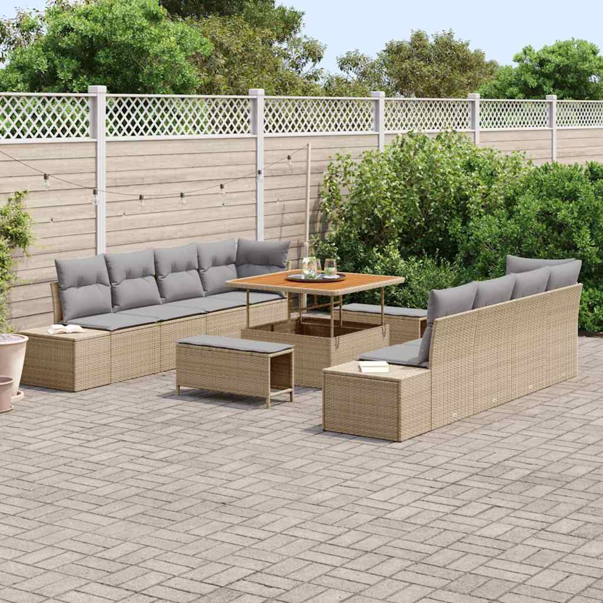 Garten-Sitzgruppe mit beigen Korbmöbeln, grauen Kissen, Holztisch und weißem Zaun, auf einer Backstein-Terrasse.