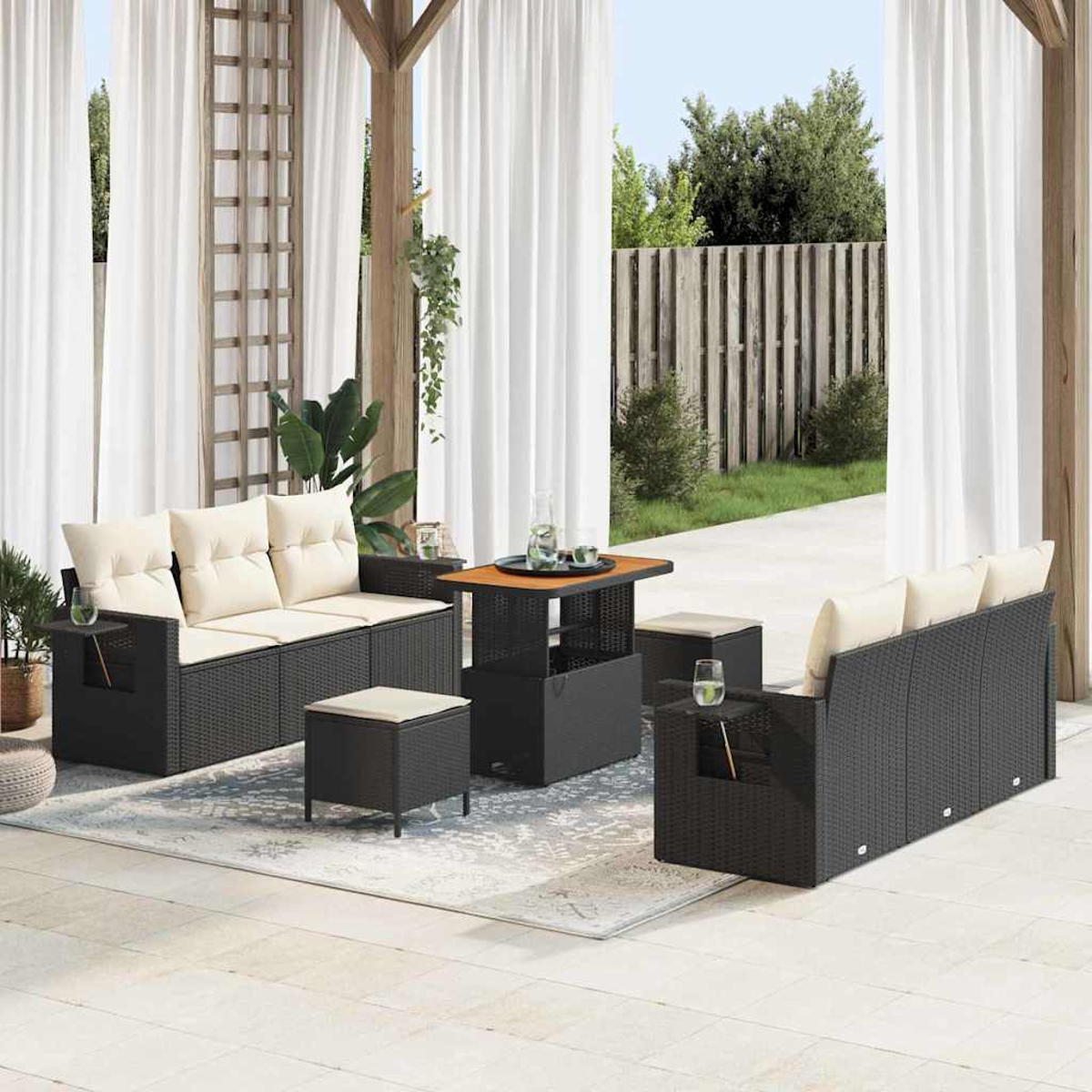 Terrassenmöbel-Set mit schwarzer Korbmöbeln und cremefarbenen Kissen. Enthält Sofas, Ottomanen und einen Tisch, vor weißen Vorhängen.
