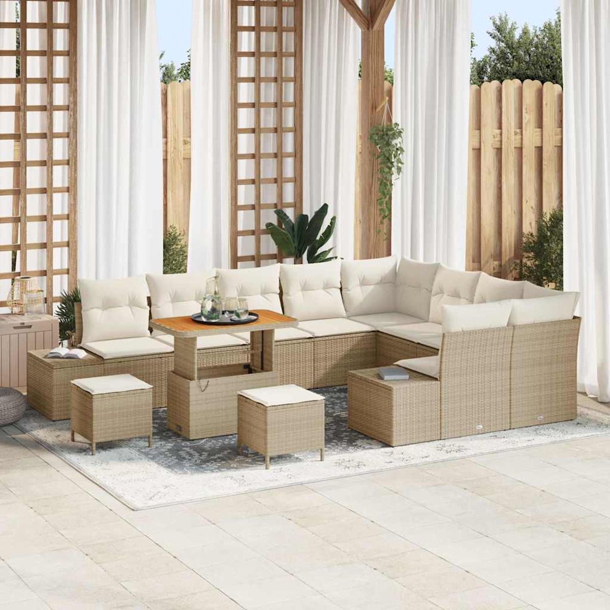 Terrassen-Set mit beigen Korbmöbeln, cremefarbenen Kissen und einem Holztisch. Enthält Sofa, Hocker und Vorhänge. Im Hintergrund ist ein Zaun zu sehen.