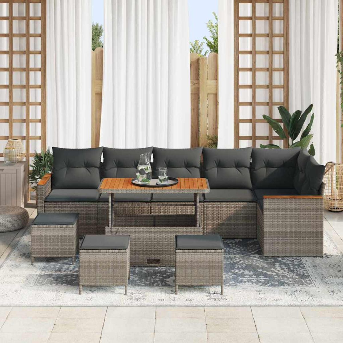 Outdoor-Terrassenset mit grauen Kissen, einem Holztisch und Hockern. Weiße Vorhänge und ein Holzzaun sind im Hintergrund.