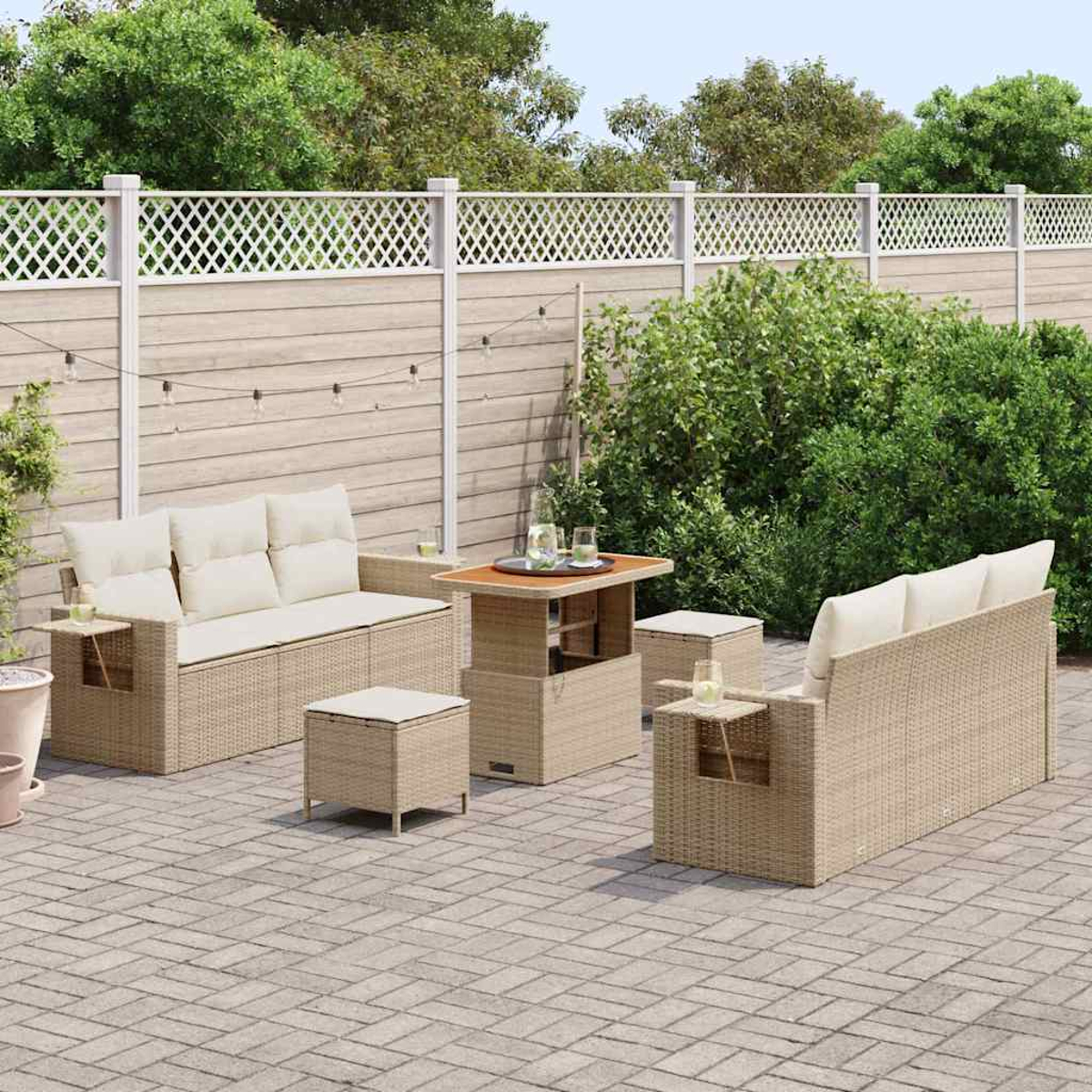 Gartenmöbel-Set aus Korbgeflecht mit beigefarbenen Kissen auf einer Backstein-Terrasse. Ein Holztisch, zwei Sofas und zwei Ottomane sind sichtbar.