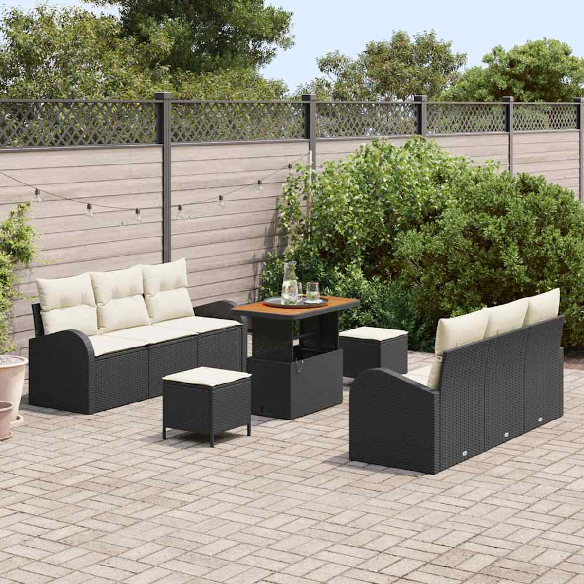 Terrassenset mit schwarzem Korbmöbeln, cremefarbenen Kissen und einem kleinen Tisch. Umgeben von einem Zaun und Grün.