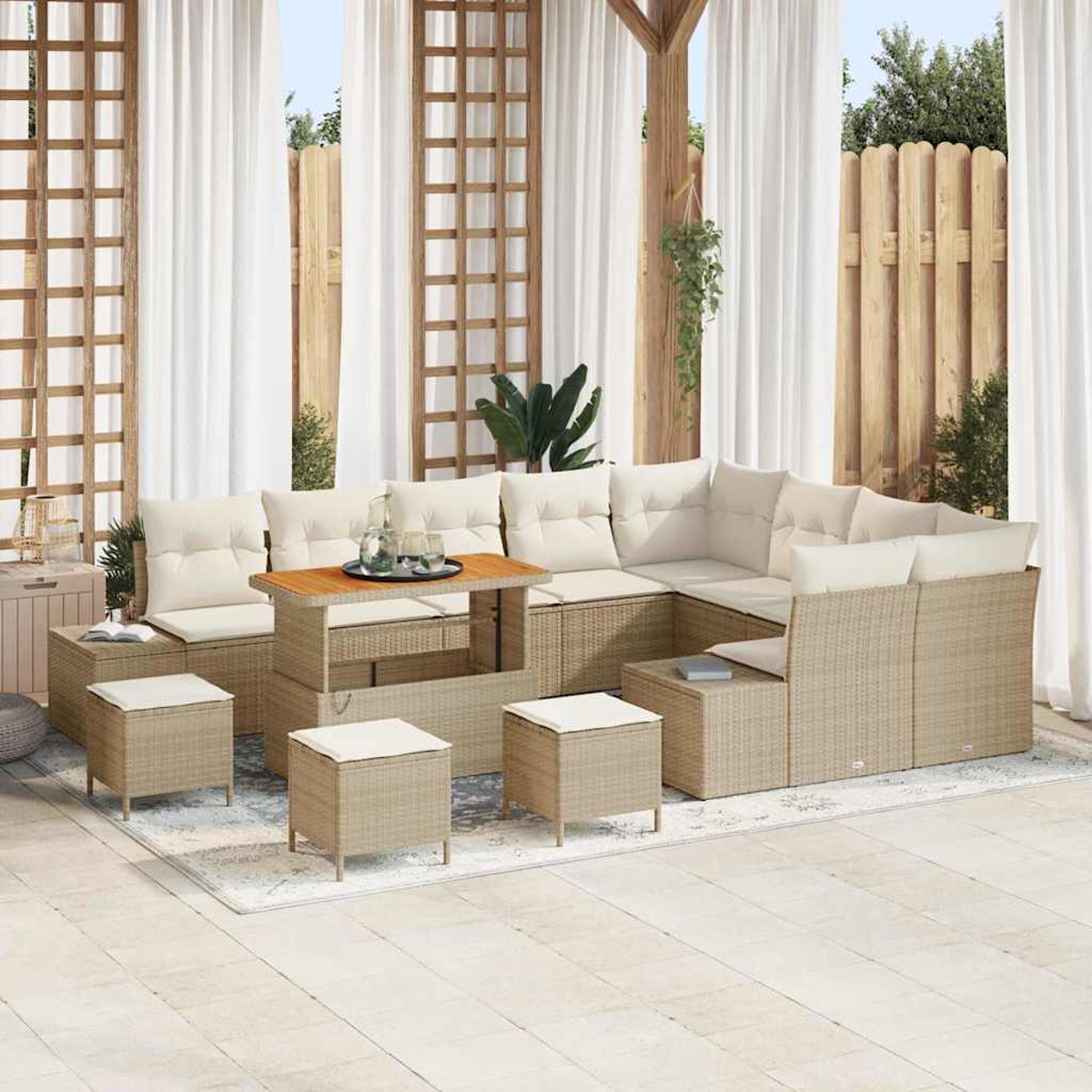 Ein beigefarbenes Ecksofa im Freien mit weißen Kissen, einem Holztisch und kleinen Hockern befindet sich auf einer Terrasse mit weißen Vorhängen.