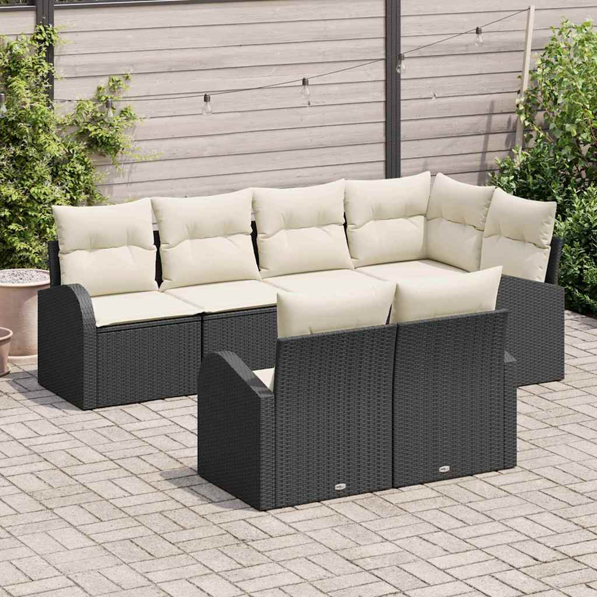 Outdoor-Sitzgruppe mit dunkelgrauem Korbrahmen und cremefarbenen Kissen. Das Set umfasst ein Sofa und zwei Sessel auf einer Steinterrasse.