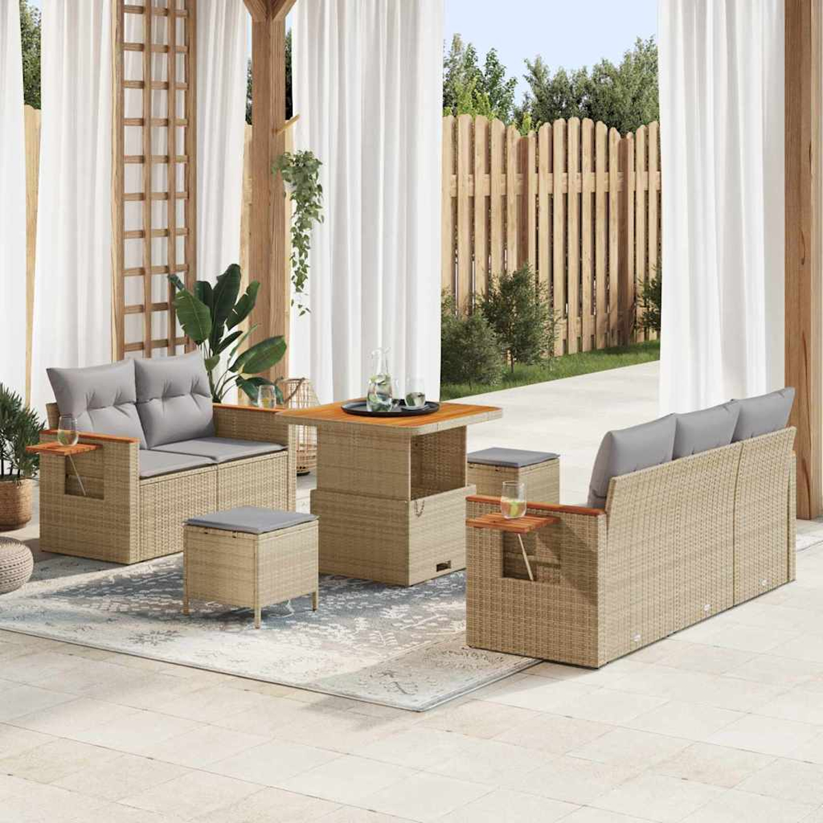 Set patio esterno con mobili in rattan, tra cui divano, tavolo e pouf. Cuscini grigi, dettagli in legno e tende bianche.