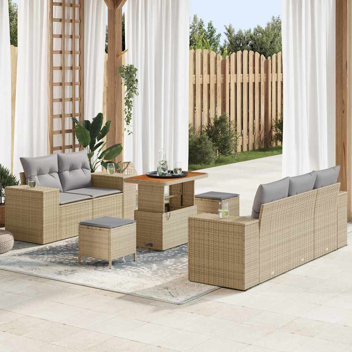Terrassenset im Freien mit beigen Korbmöbeln, grauen Kissen und einem Holztisch. Weiße Vorhänge und ein Holzzaun sind im Hintergrund.