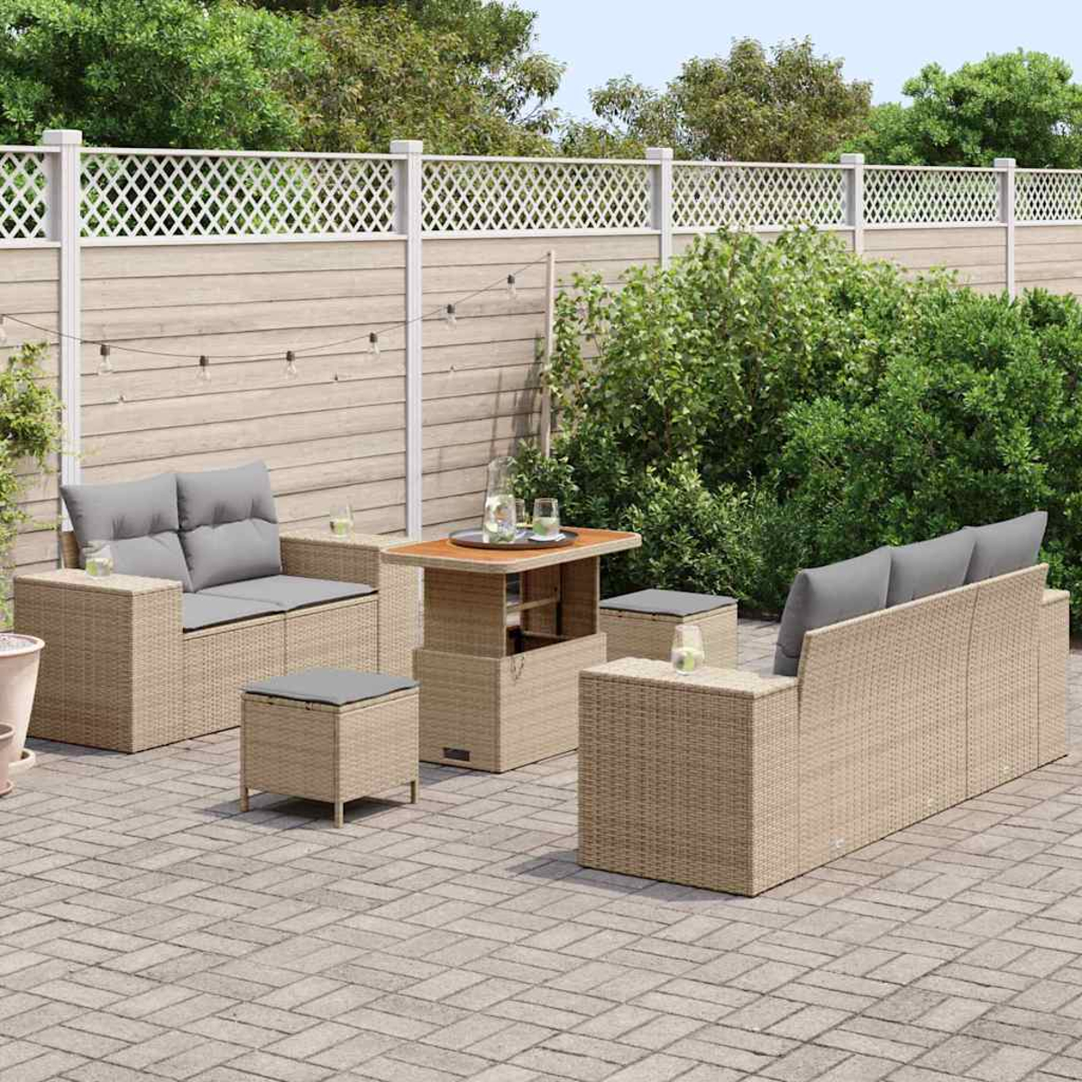 Garten-Terrassenset mit Sofa, Stühlen, Tisch und Ottomanen auf einer Backsteinterrasse. Im Hintergrund ein Holzzaun mit Gitter.