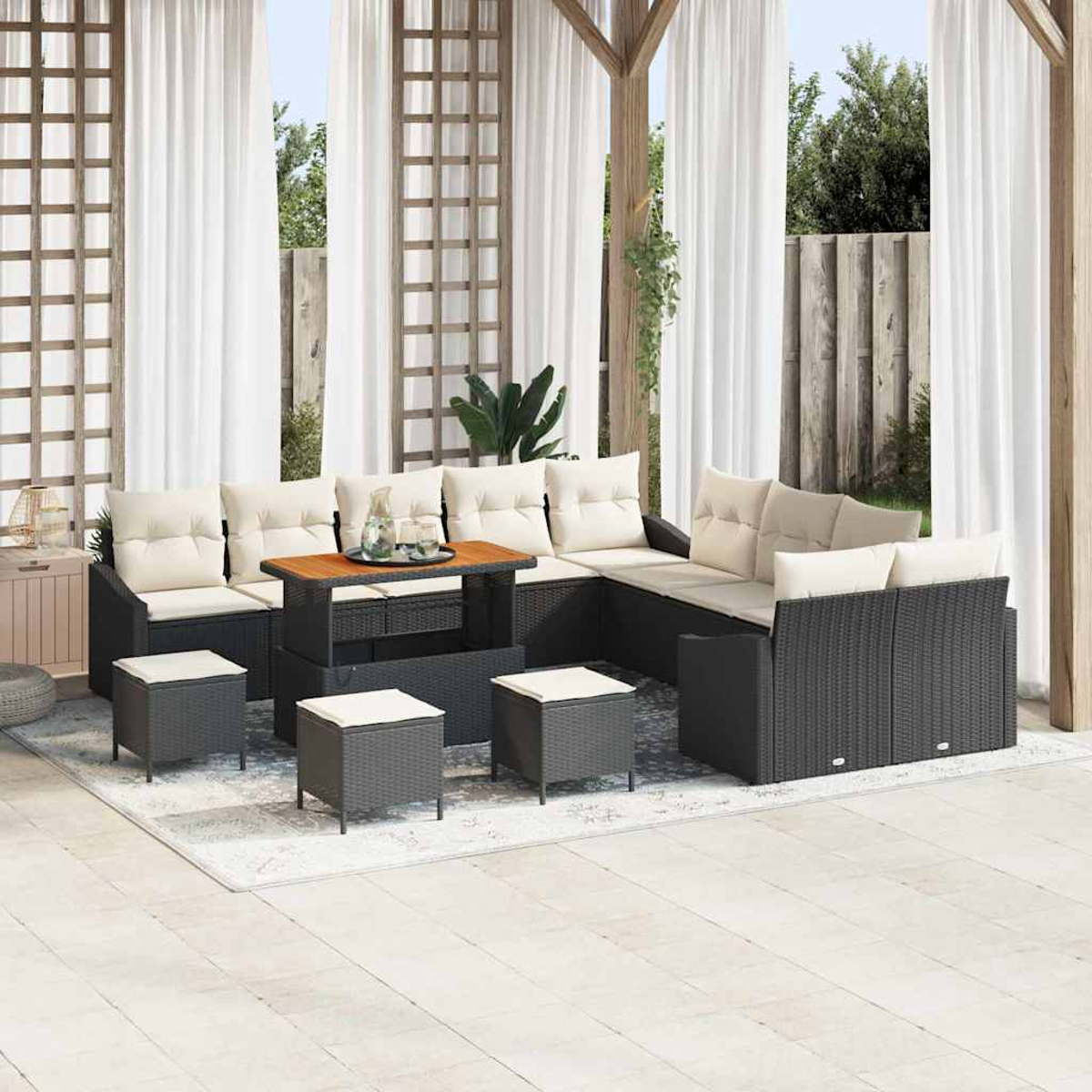 Terrassen-Set mit schwarzem Korbmöbeln, beigen Kissen, Holztisch und passenden Hockern auf hellem Teppich, Vorhängen und Pflanzen.