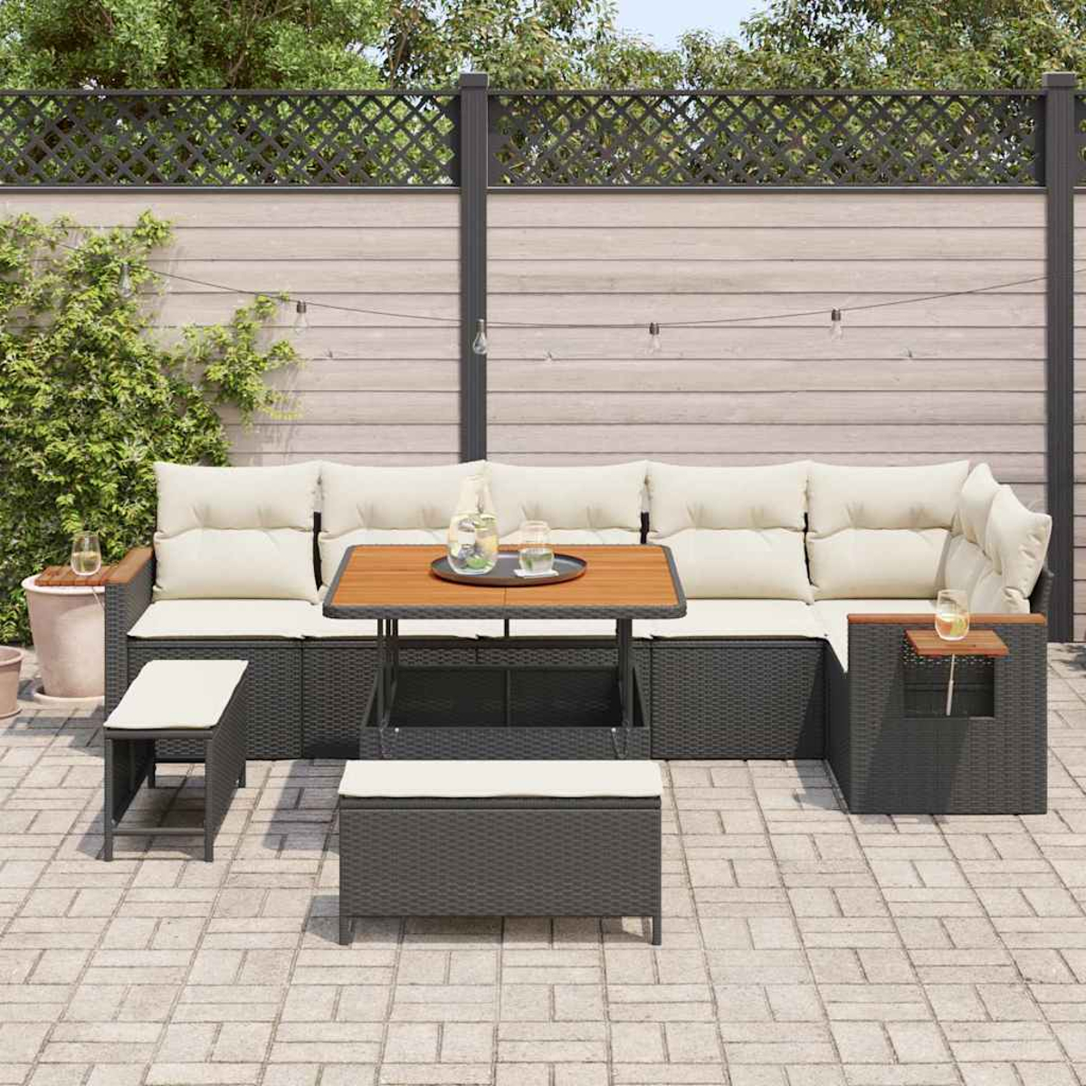 Set di sedute per esterni con divano componibile, tavolo e due panche. Il set si trova in un cortile con recinzione e luci.