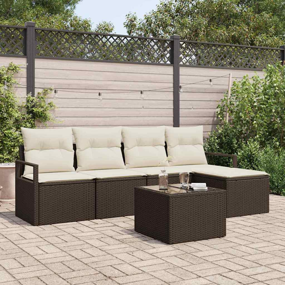 Outdoor-Rattan-Sofagarnitur mit cremefarbenen Kissen, kleinem Tisch und Gläsern. Auf einer Terrasse mit Zaun im Hintergrund.