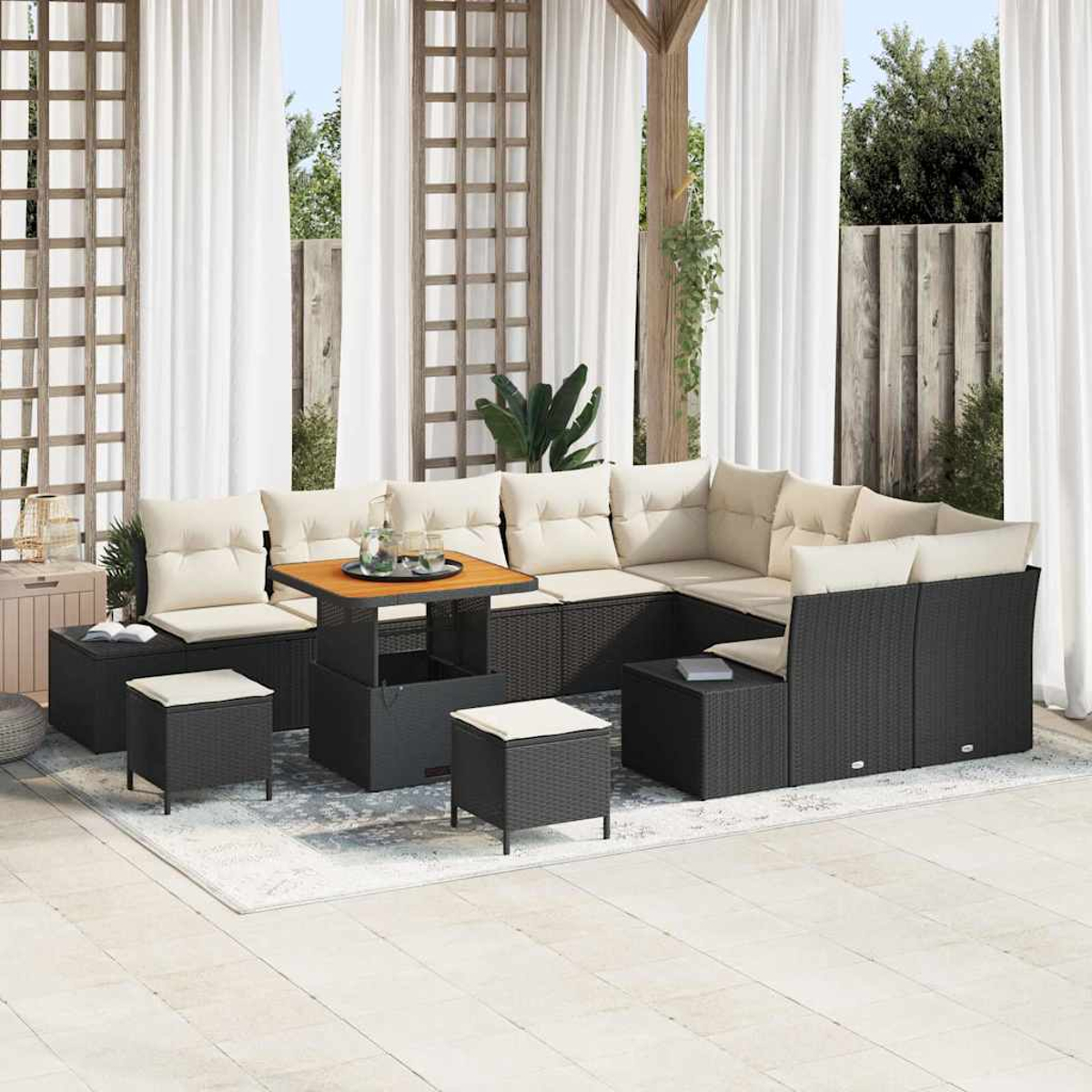 Juego de patio al aire libre con muebles de mimbre negro, cojines beige, mesa de madera. Cortinas blancas y enrejado de madera en el fondo, sobre una alfombra.