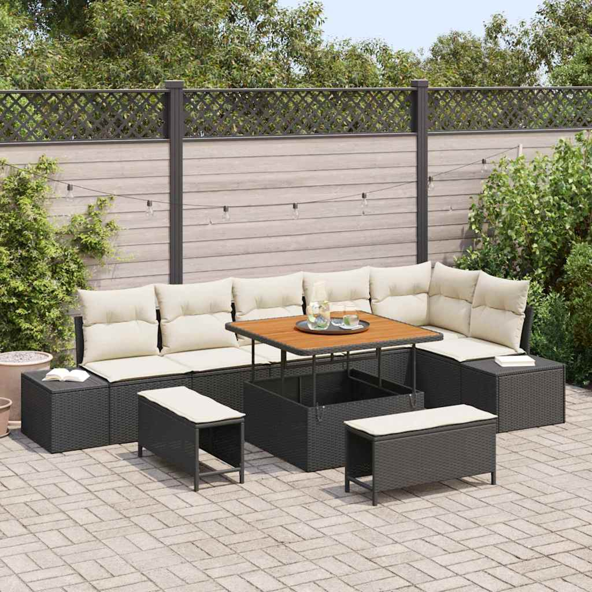 Outdoor-Ecksofa mit beigen Kissen, Holztisch und Bänken auf einer Backstein-Terrasse. Im Hintergrund ein Zaun und Grün.