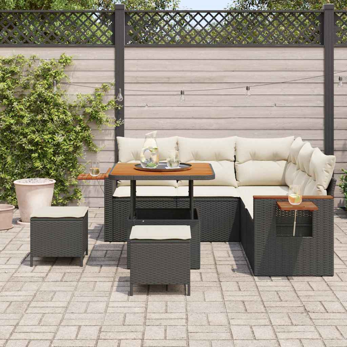 Outdoor-Sitzbereich mit Ecksofa, Tisch, Hockern und Holzzaun. Getränke und Pflanzen sind sichtbar.