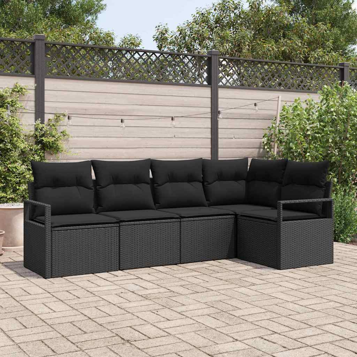 Sofá seccional exterior de mimbre negro en un patio de ladrillos. El fondo incluye una valla de madera y follaje.