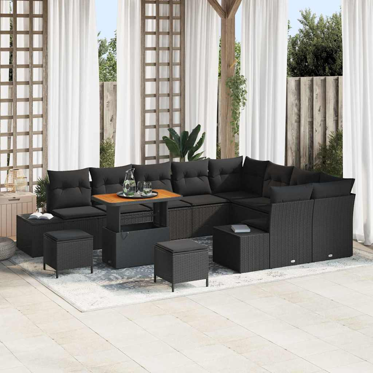 Outdoor-Ecksofa mit schwarzen Kissen. Ein Holztisch, Ottomanen und ein Teppich befinden sich auf der Terrasse. Weiße Vorhänge im Hintergrund.