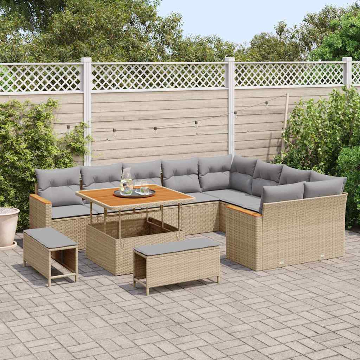 Outdoor-Rattanmöbelset: Ecksofa, Couchtisch und zwei Ottomanen, alle mit grauen Kissen, auf einer Terrasse.