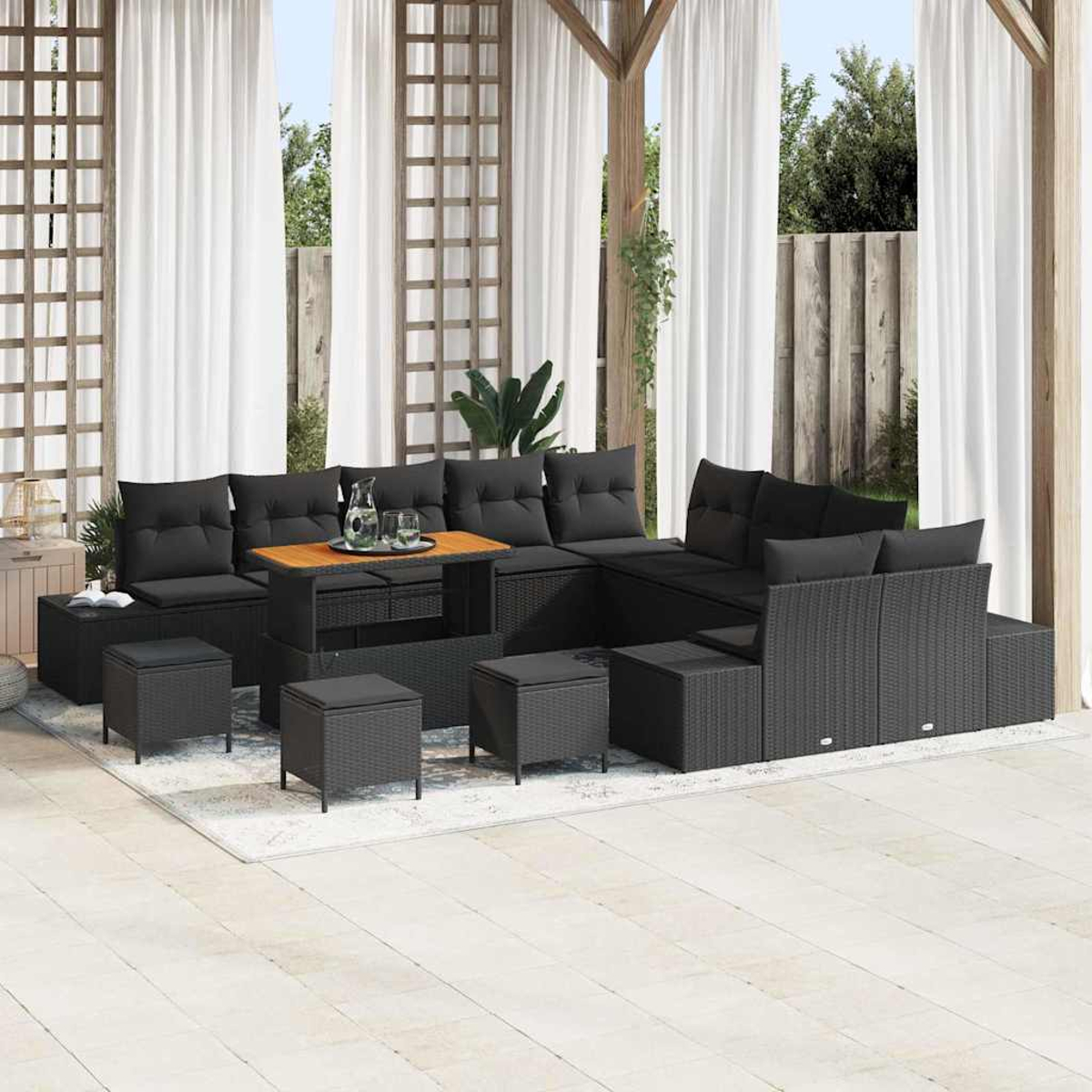 Outdoor-Ecksofa mit schwarzen Kissen. Inklusive Ottomanen und einem Couchtisch, auf einem gemusterten Teppich, mit Pergola und Vorhängen.