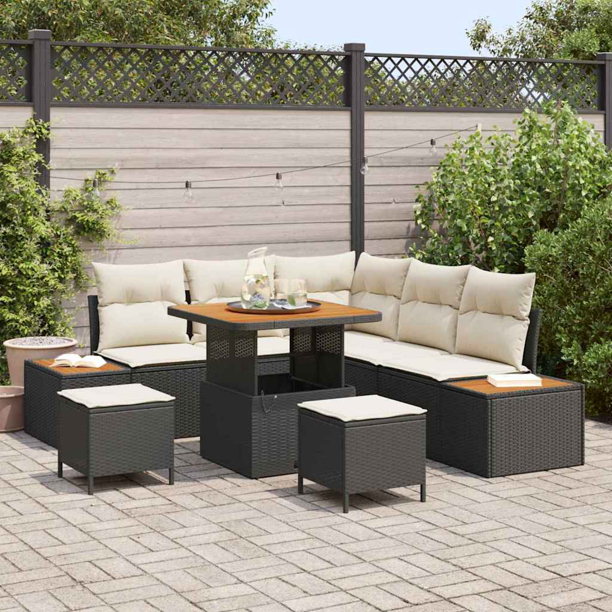 Terrassengarnitur mit Sofa, Tisch und Hockern. Beige Kissen, Tischplatte aus Holz und schwarze Webmöbel auf einer Ziegelterrasse.