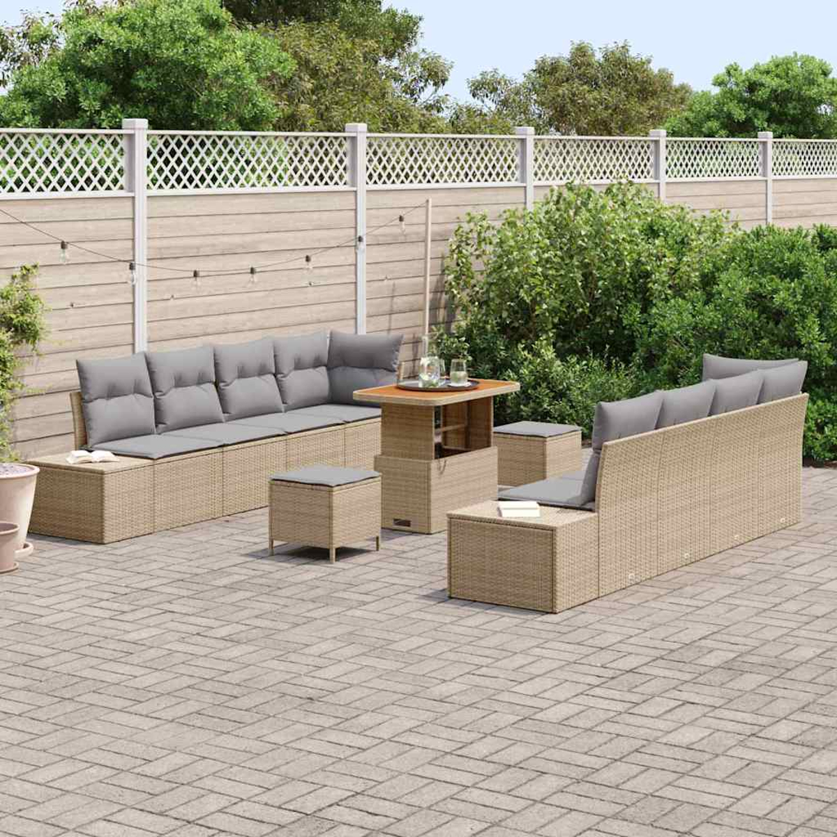 Terrassenmöbel-Set im Freien mit beigen Korbmöbeln und grauen Kissen. Enthält Sofa, Tisch, Ottomane und einen Gitterzaun im Hintergrund.