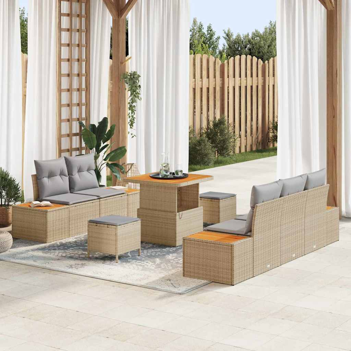 Outdoor-Sitzgruppe mit beigen, gewebten Möbeln, grauen Kissen und einem Holztisch. Vorhänge und ein Holzzaun im Hintergrund.