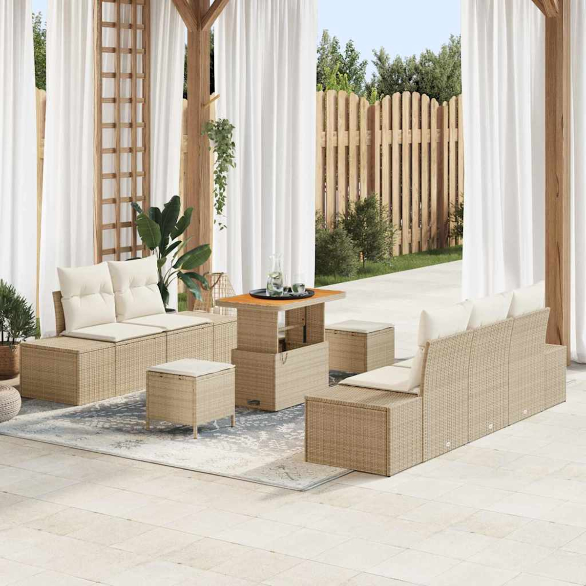 Outdoor-Korbmöbel-Set mit Kissen, Tisch und Hockern auf einer Terrasse mit Vorhängen und Holzzaun im Hintergrund.