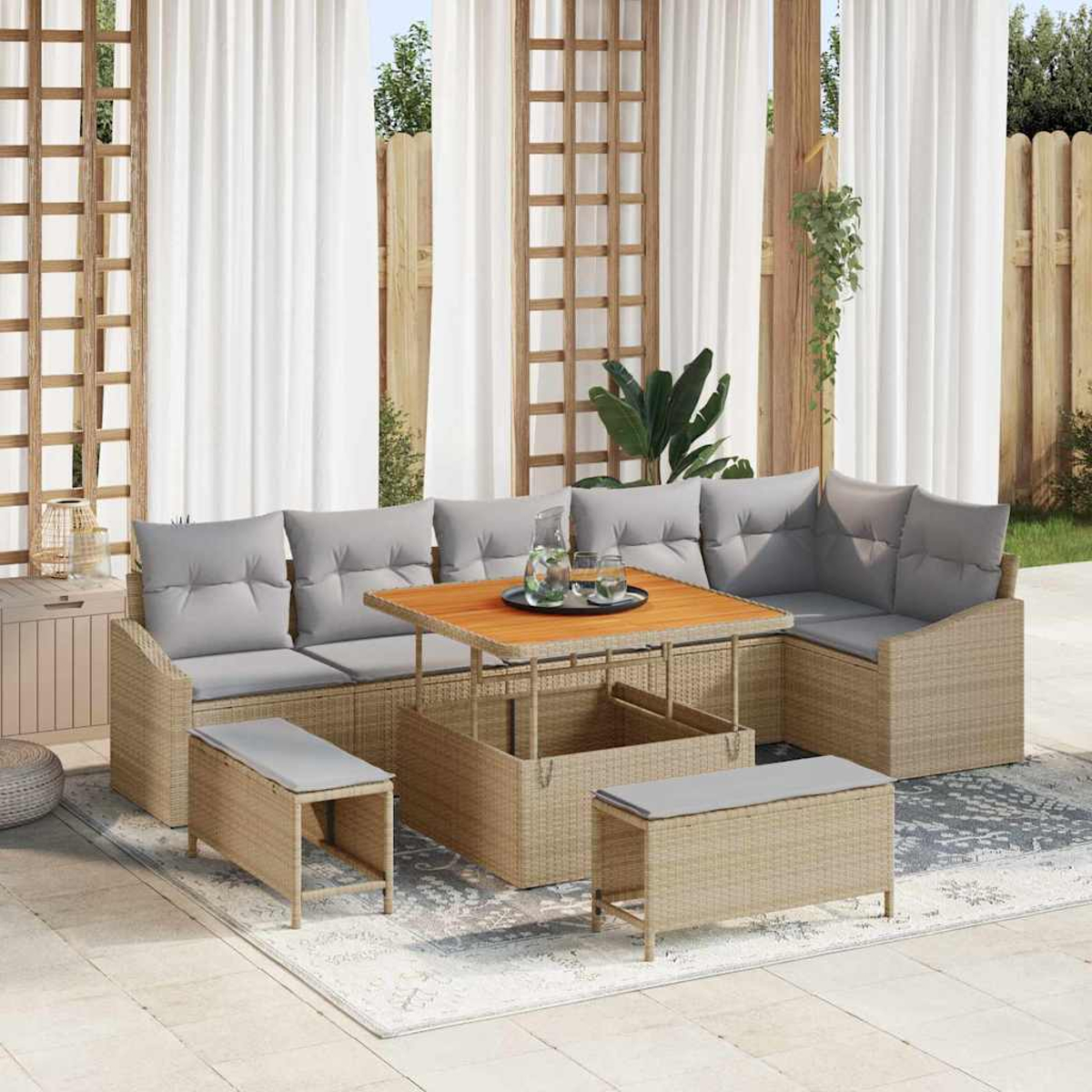 Outdoor-Rattansofa mit grauen Kissen und Holztisch. Vorhänge und Holzzaun im Hintergrund.