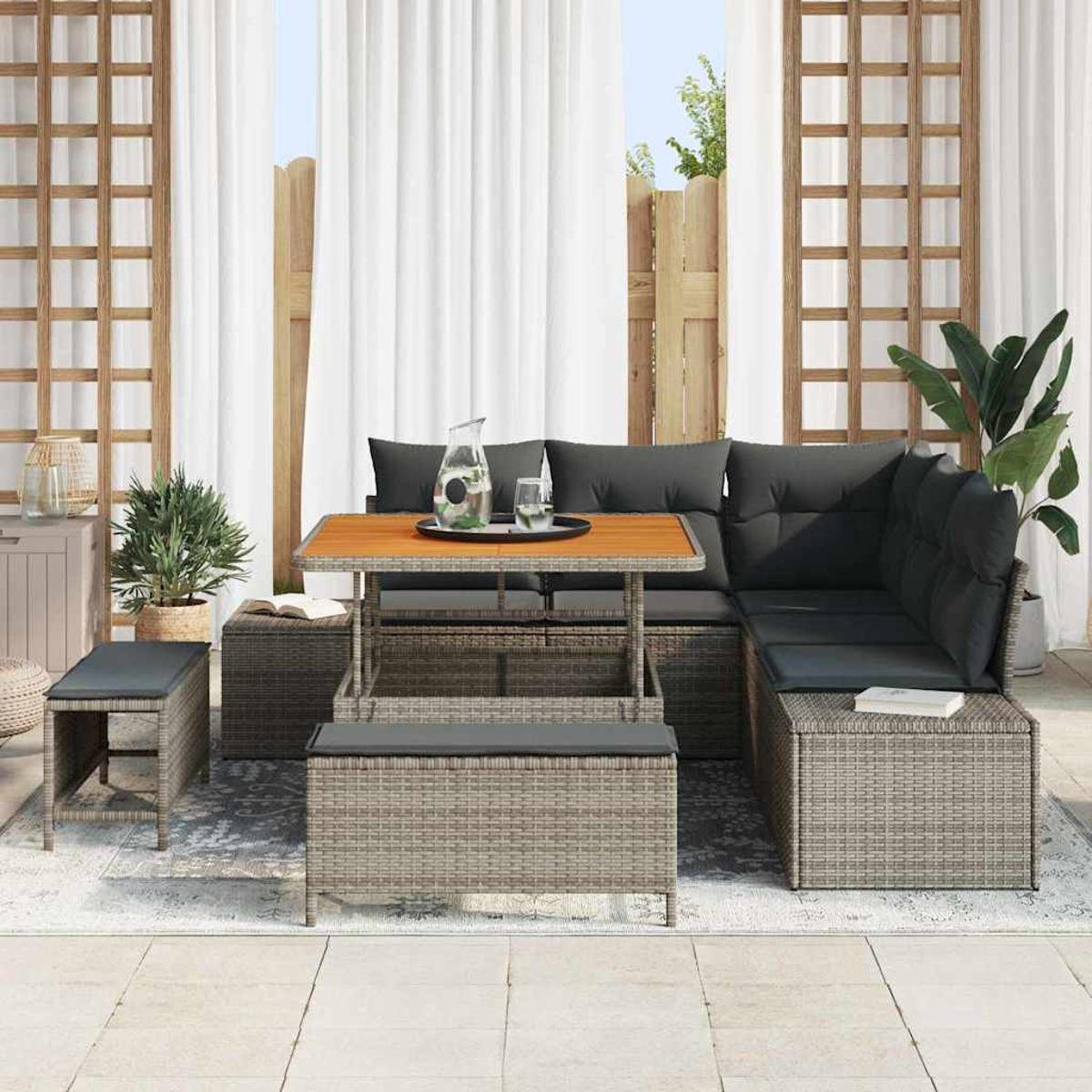 Outdoor-Sofa mit Kissen, Holztisch mit Getränken, Hocker, Pflanzen und Vorhängen.