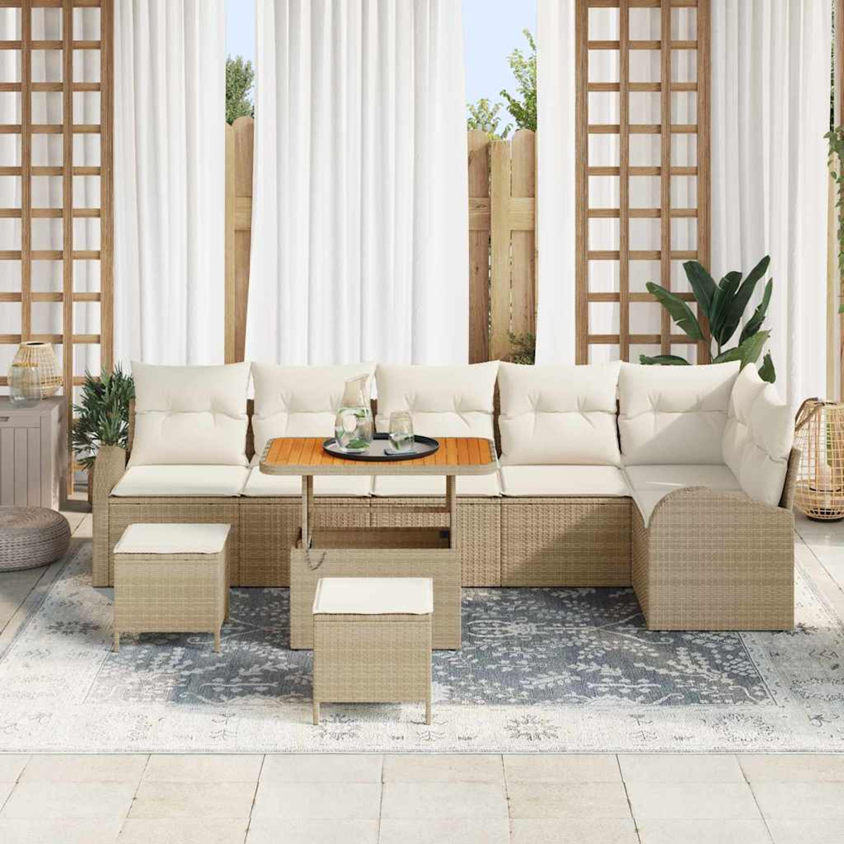 Set da patio esterno con cuscini beige, un tavolo e sgabelli abbinati su un tappeto fantasia. Tende bianche e traliccio in legno sullo sfondo.