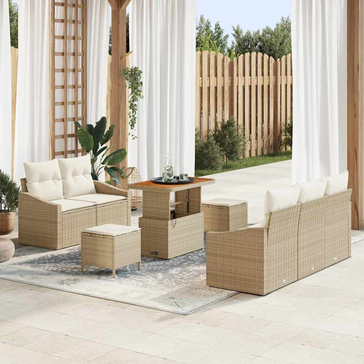 Gartenmöbel-Set aus Weidengeflecht auf einer Terrasse. Enthält Sofas, Ottomanen und einen Couchtisch. Vorhänge und ein Holzzaun befinden sich im Hintergrund.
