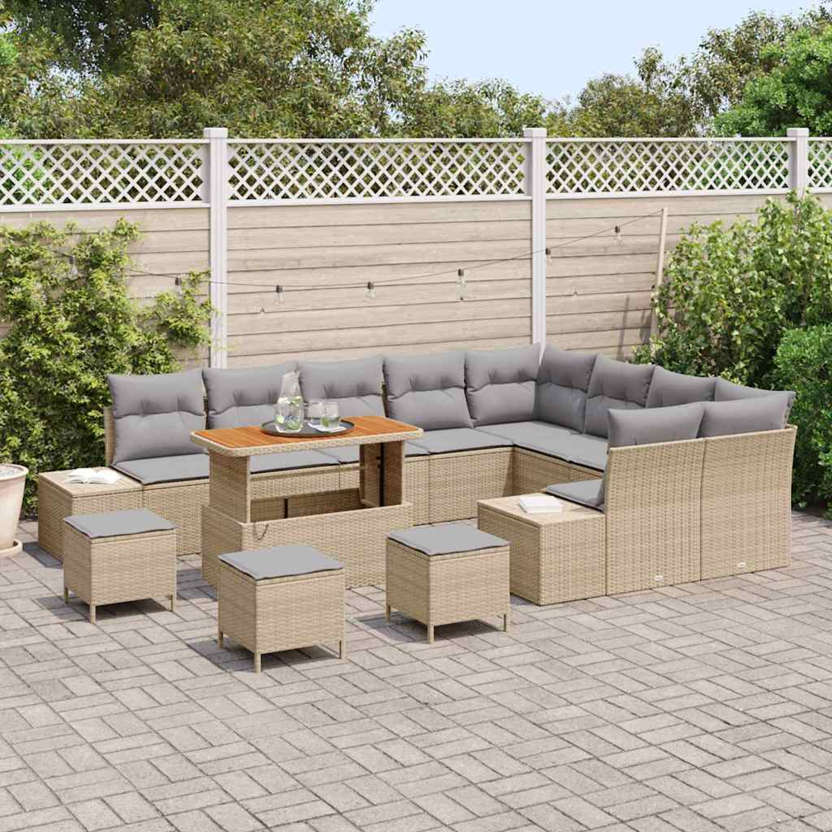 Outdoor-Ecksofa mit grauen Kissen, Ottomanen und einem Tisch auf einer Terrasse. Ein weißer Zaun und Pflanzen befinden sich im Hintergrund.