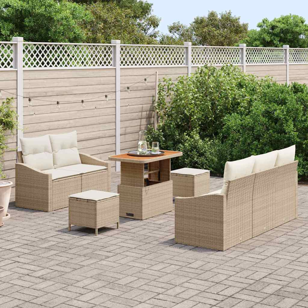 Outdoor-Terrassenset mit Korbmöbeln. Beinhaltet Sofa, Stühle, Tisch und Hocker auf einer Ziegelsteinterrasse mit Zaun.