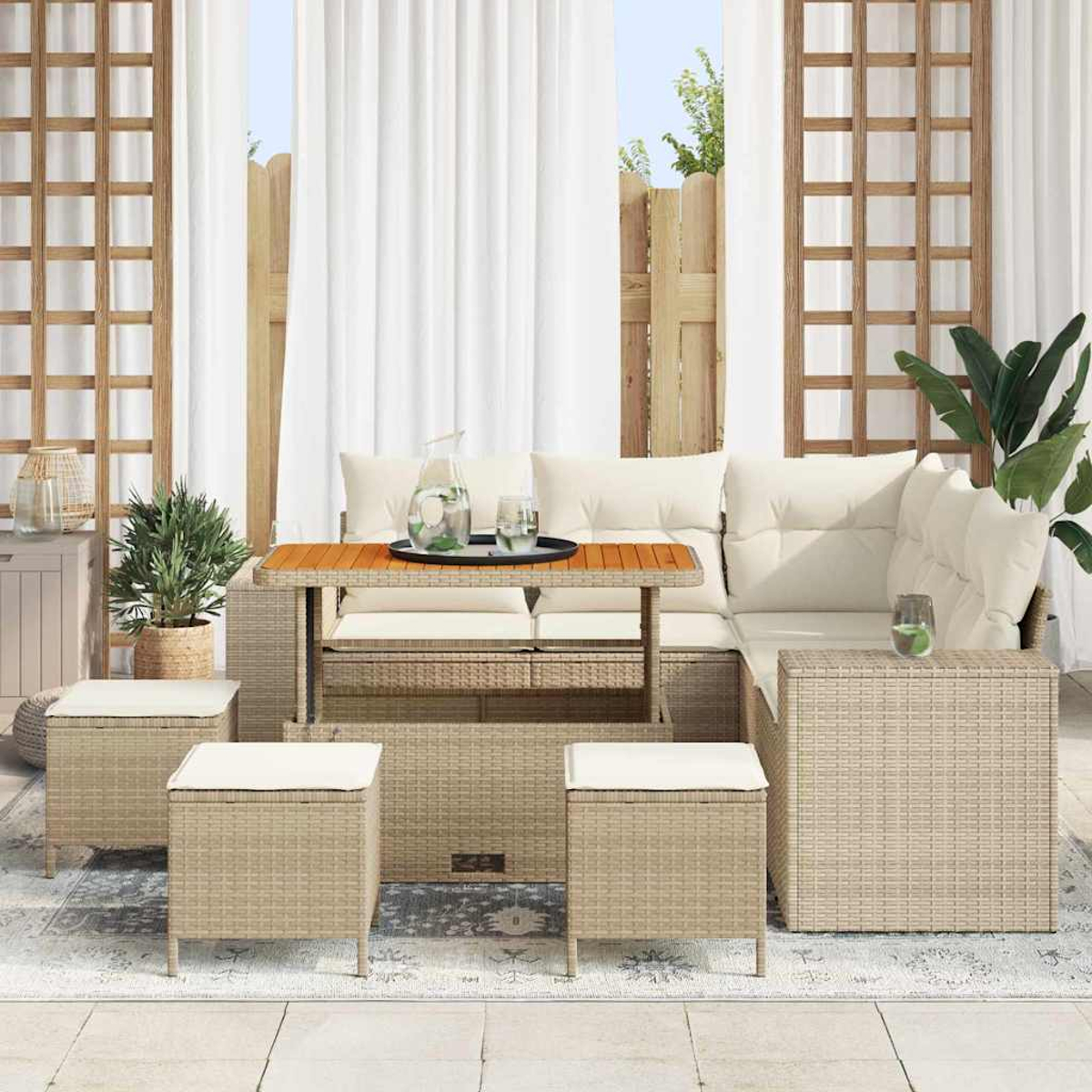 Terrassenset mit beigen Korbmöbeln, weißen Kissen und einem Holztisch. Hintergrund: Vorhänge, Zaun und Grün.