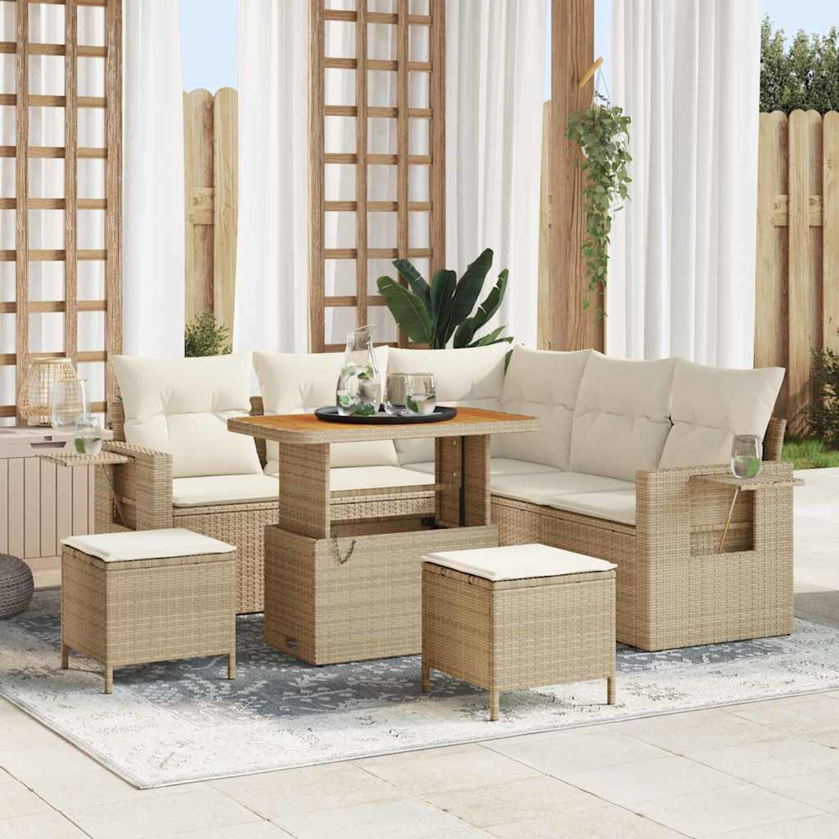 Outdoor-Rattan-Möbelset, bestehend aus Sofa, Tisch und Ottomanen, auf einem gemusterten Teppich. Weiße Vorhänge und Holzzaun im Hintergrund.