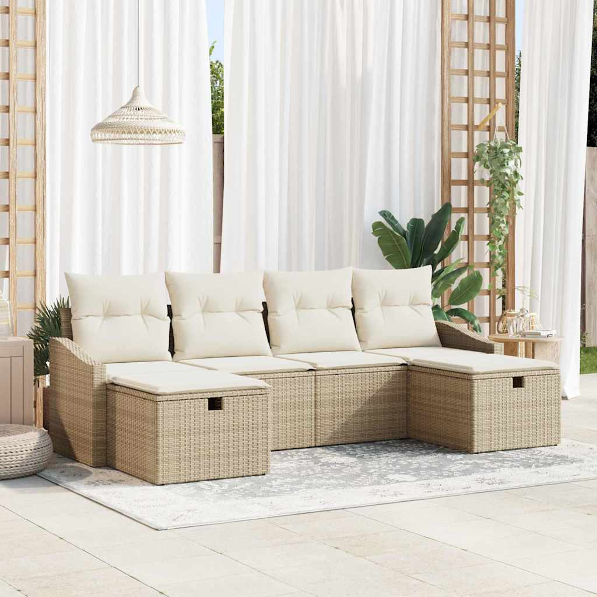 Ein beiges Korbsessel-Sofa mit cremefarbenen Kissen steht auf einer Terrasse. Weiße Vorhänge und eine Hängeleuchte sind im Hintergrund.