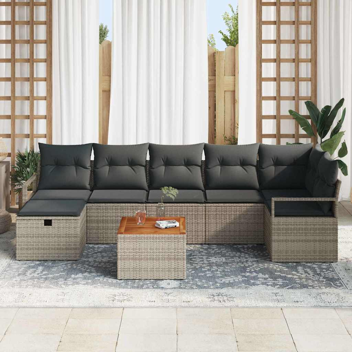 Outdoor-Ecksofa mit grauen Kissen und einem Holztisch auf einem gemusterten Teppich, mit weißen Vorhängen und Pflanzen im Hintergrund.