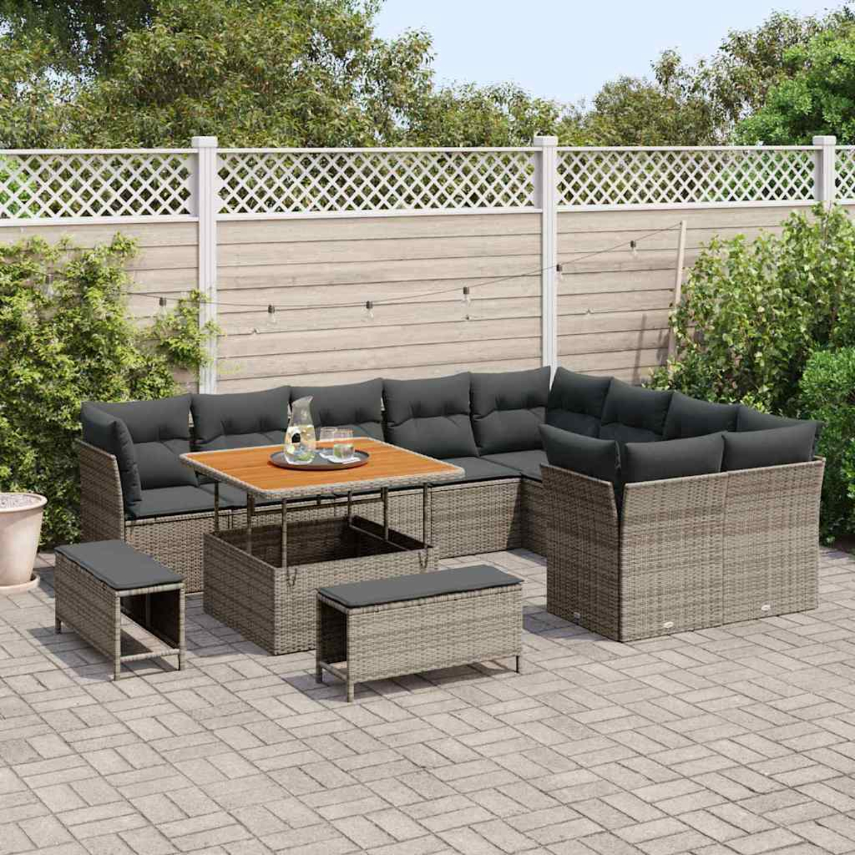 Outdoor-Terrassenset mit grauen Kissen. Enthält einen Tisch, Bänke und Ecksofa. Im Hintergrund sind ein Zaun und Blätter zu sehen.