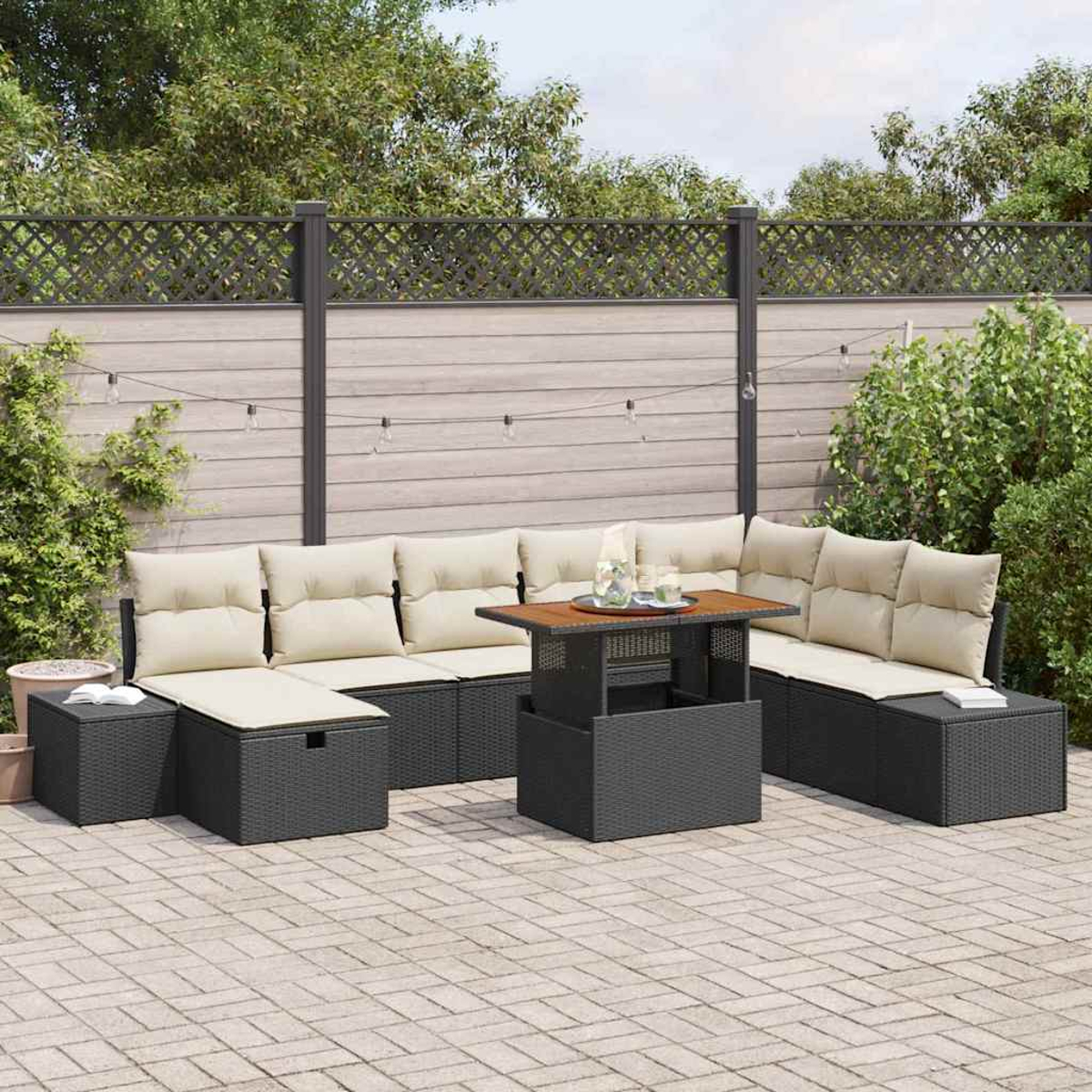 Terrassenmöbel-Set mit schwarzem Korbmöbel, beigen Kissen und Holztisch. Die Szene spielt sich auf einer gepflasterten Terrasse ab.