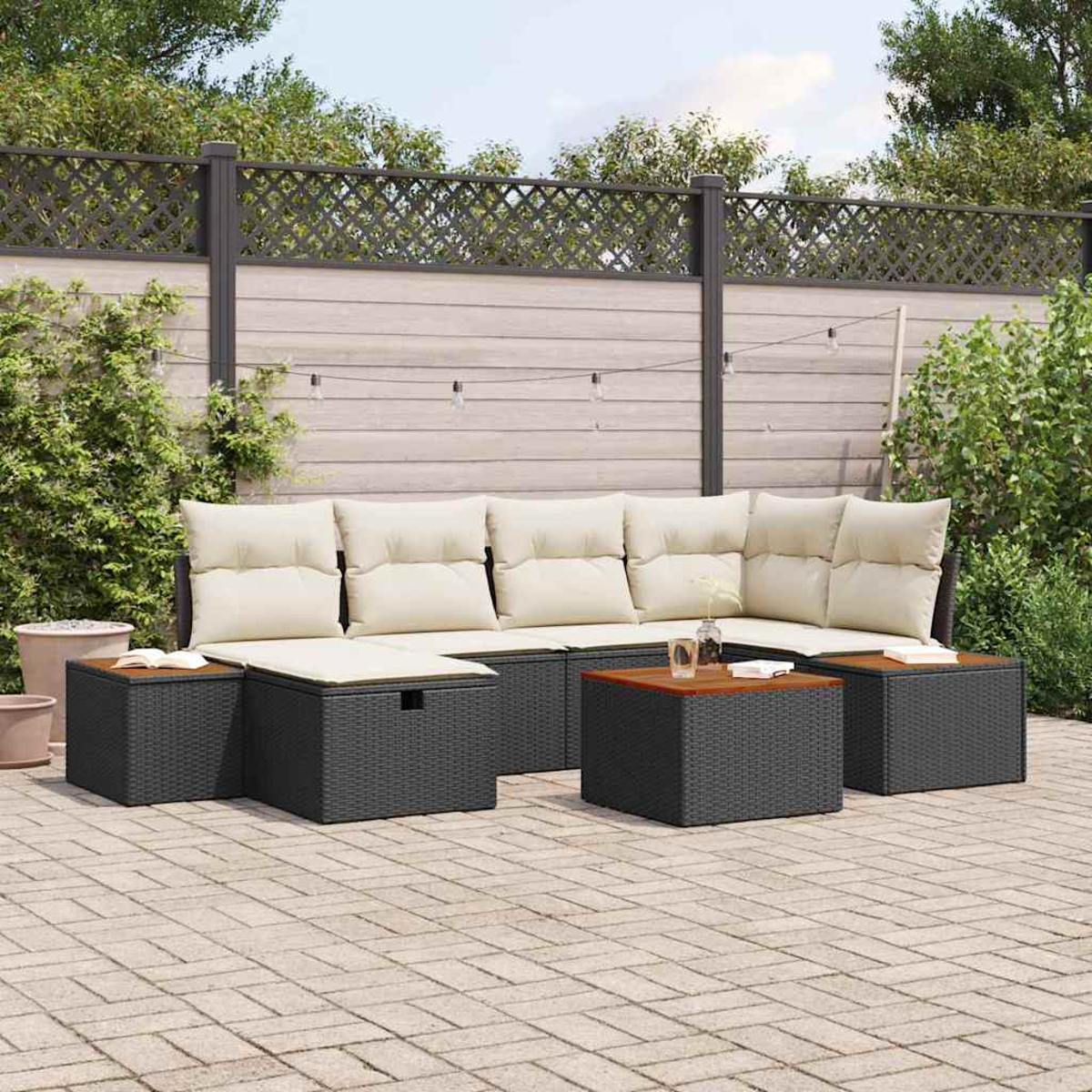 Garten-Terrassenset mit grauen Korbmöbeln, beigefarbenen Kissen und Holztisch. Auf einer Ziegelterrasse mit Holzzaun im Hintergrund.