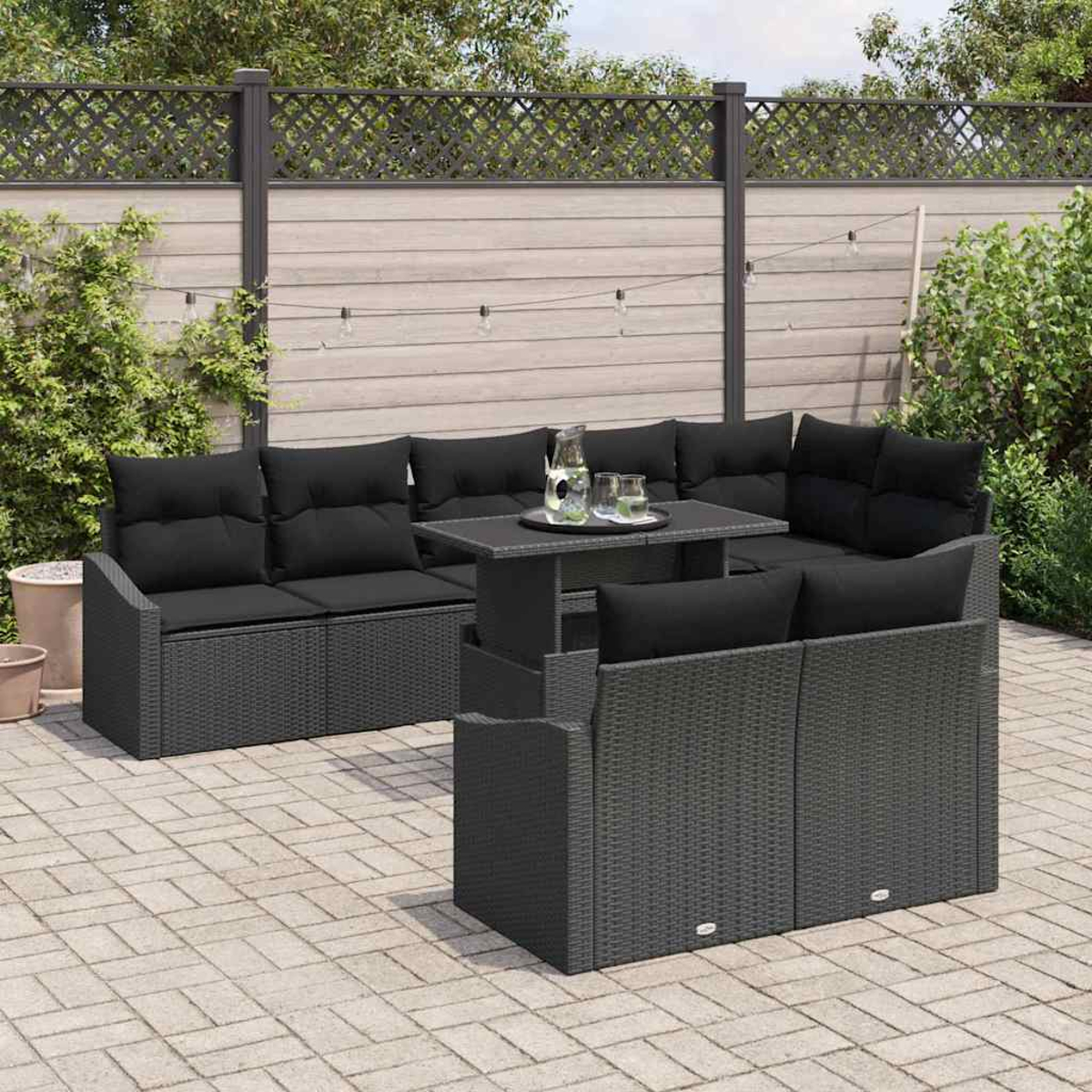 Graues Ecksofa mit schwarzen Kissen, passendem Tisch mit Getränken und Holzzaun im Hintergrund.