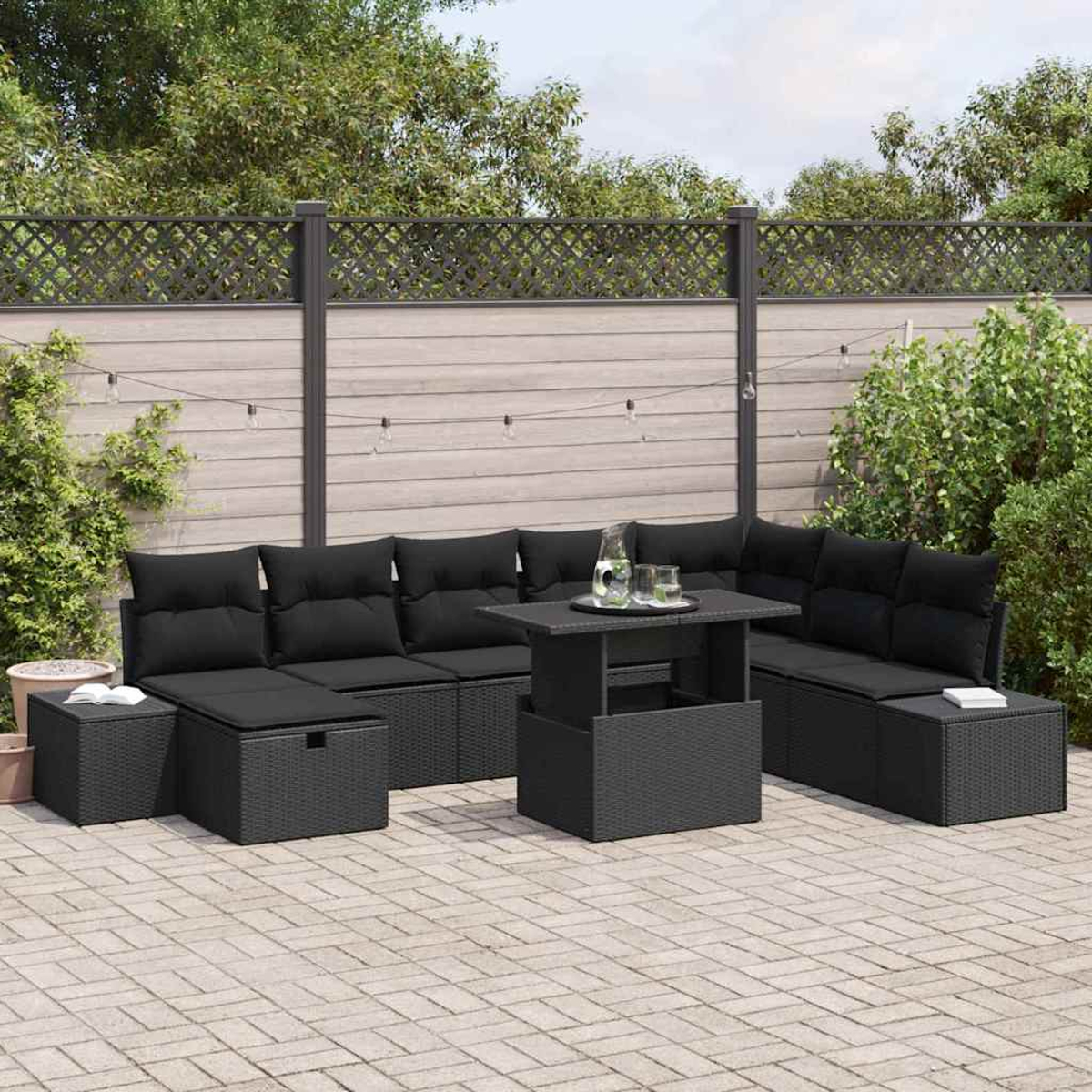 Garten-Terrassenset mit schwarzen Kissen, Tisch mit Gläsern und einem Zaun im Hintergrund. Die Szene spielt auf einer Ziegelterrasse.